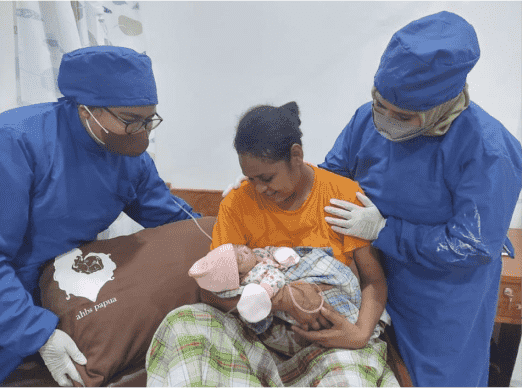 A woman and two doctors celebrating a birth